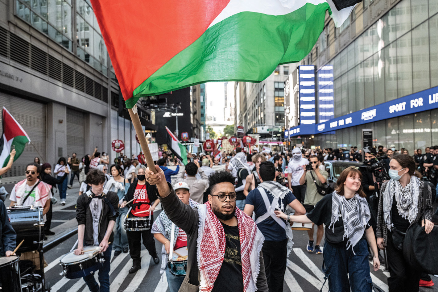 Midtown Manhattan street march 2024 — Manolo De Los Santos leading protest with large Palestinian flag